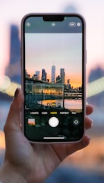 A person using a smartphone with a city skyline in the background.