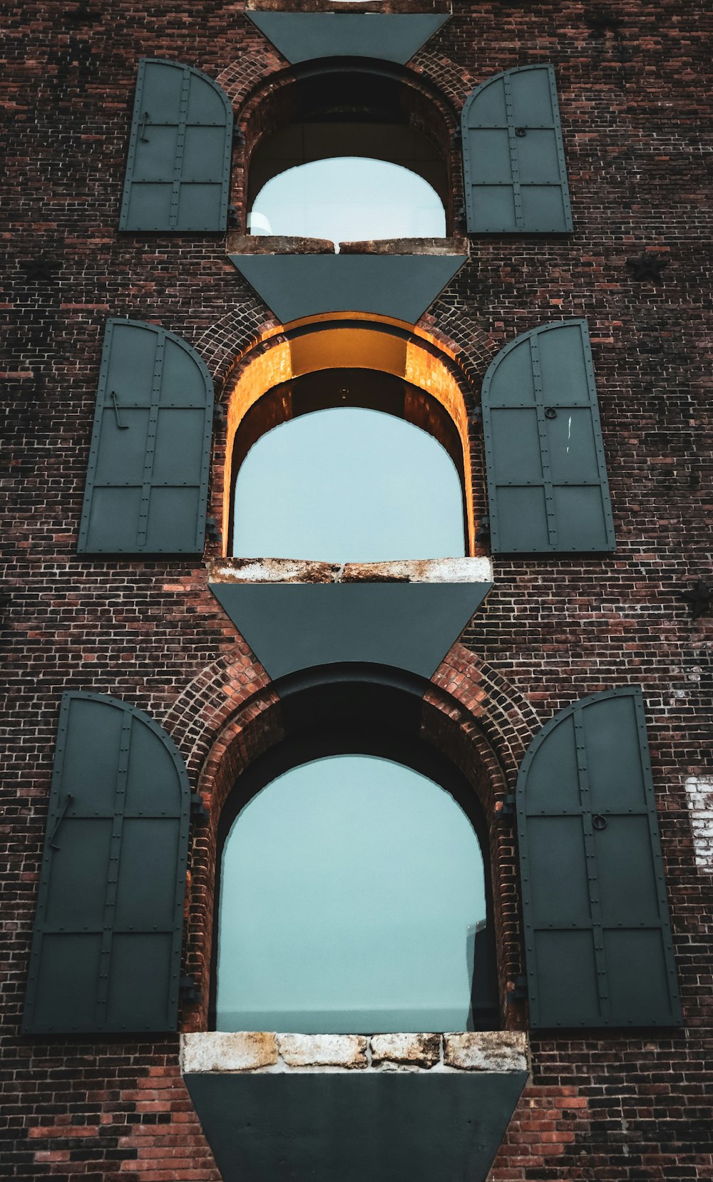 a tall brick building with windows and shutters