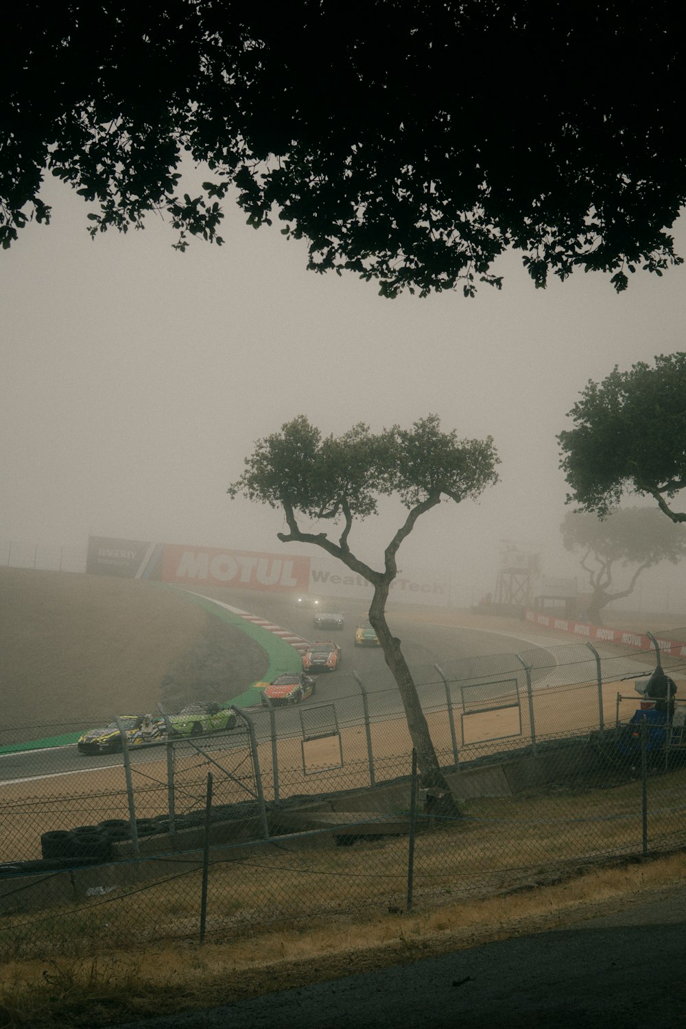 a foggy race track with cars driving on it