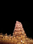 Golden-lit temple facade glowing against a deep black night sky.