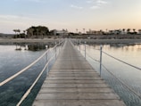 A wooden pier stretching into the calm, crystal-clear waters of Trincomalee beach at sunrise.