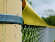 Close-up of a sturdy metal fence post securely anchored in concrete.