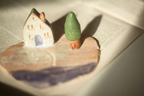 A delicate miniature house perched on a wooden shelf, bathed in warm afternoon light.