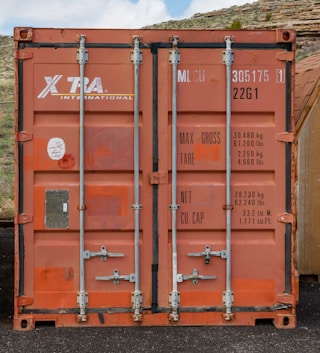 a large orange container sitting on top of a gravel road