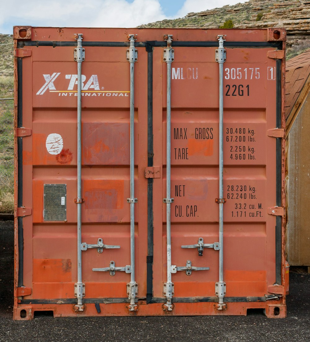 a large orange container sitting on top of a gravel road