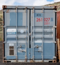 a couple of blue containers sitting on top of a dirt field