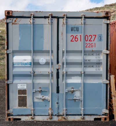 a couple of blue containers sitting on top of a dirt field