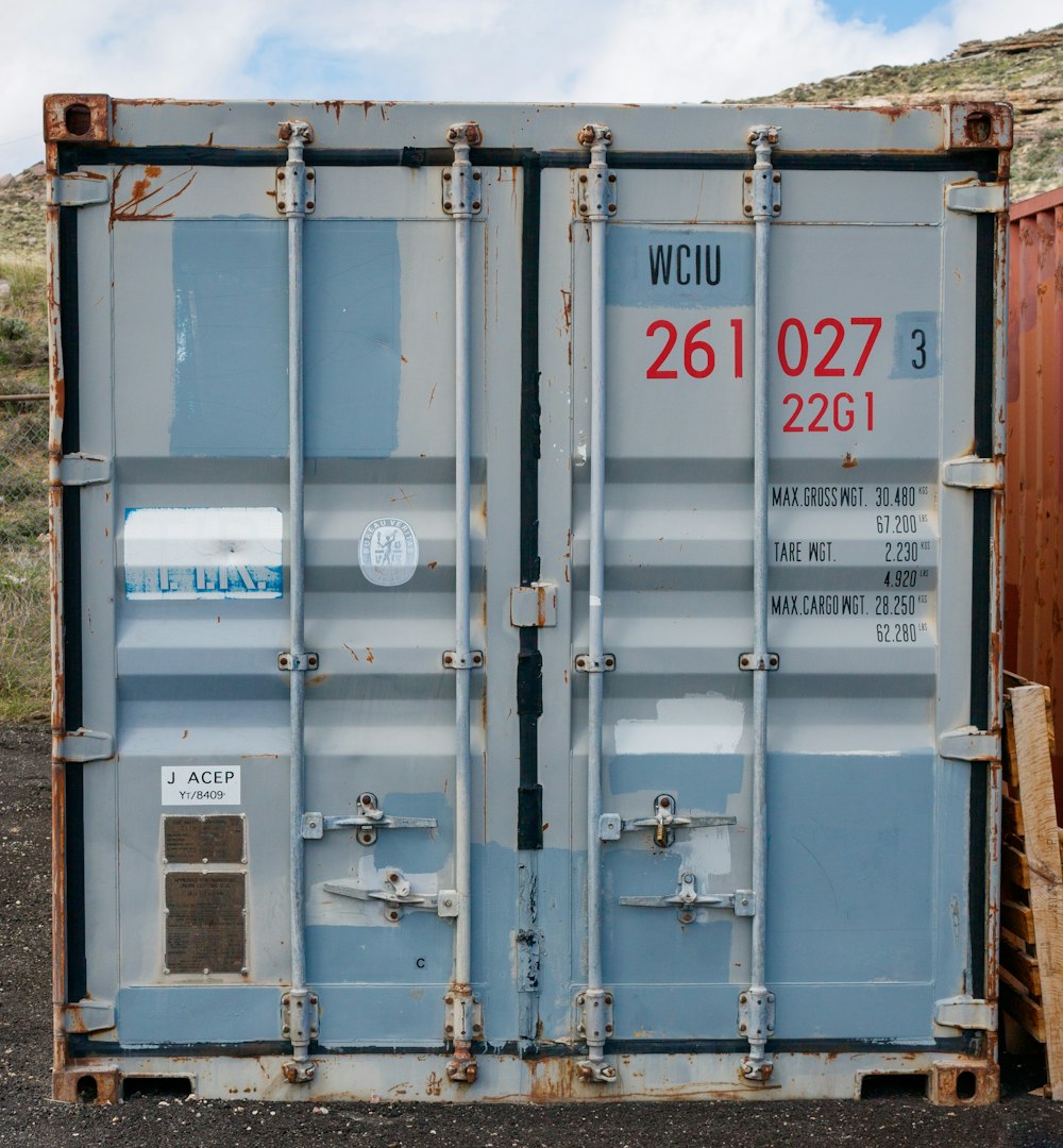 a couple of blue containers sitting on top of a dirt field