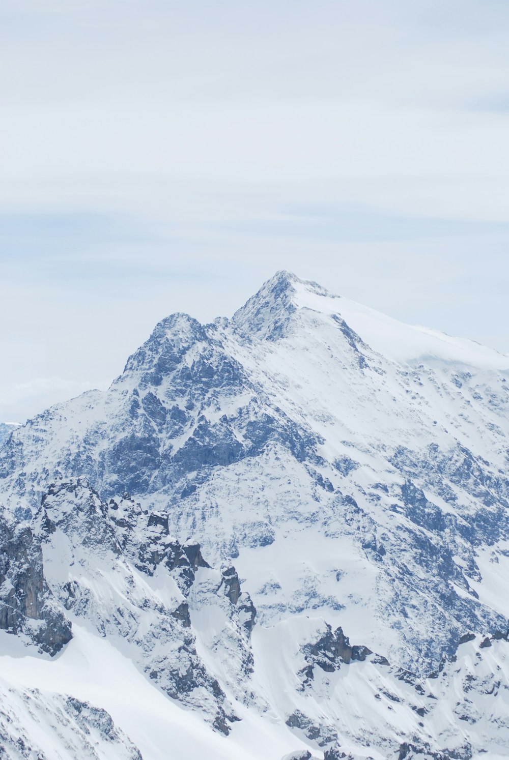 a mountain covered in snow under a cloudy sky