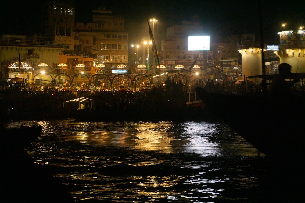 a large crowd of people standing around a river at night