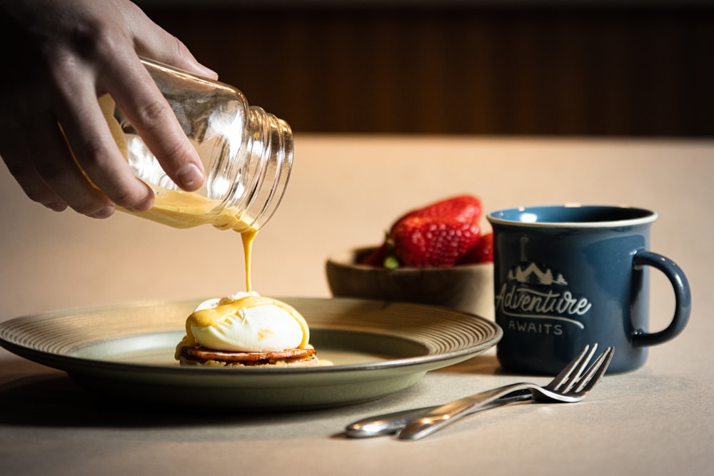 a person drizzling syrup onto a plate of food