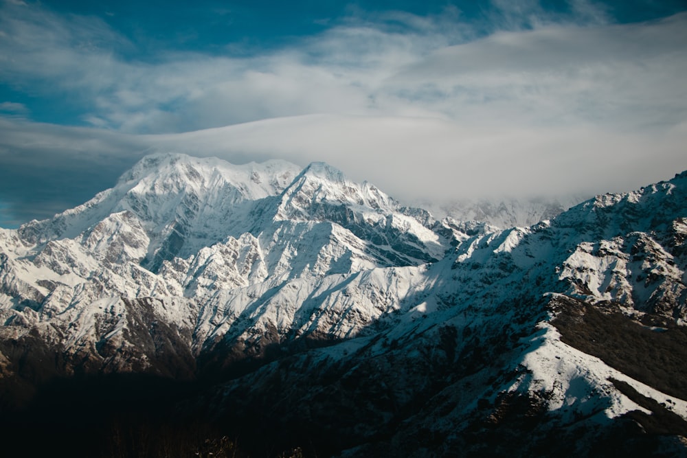 a snow covered mountain range under a cloudy sky