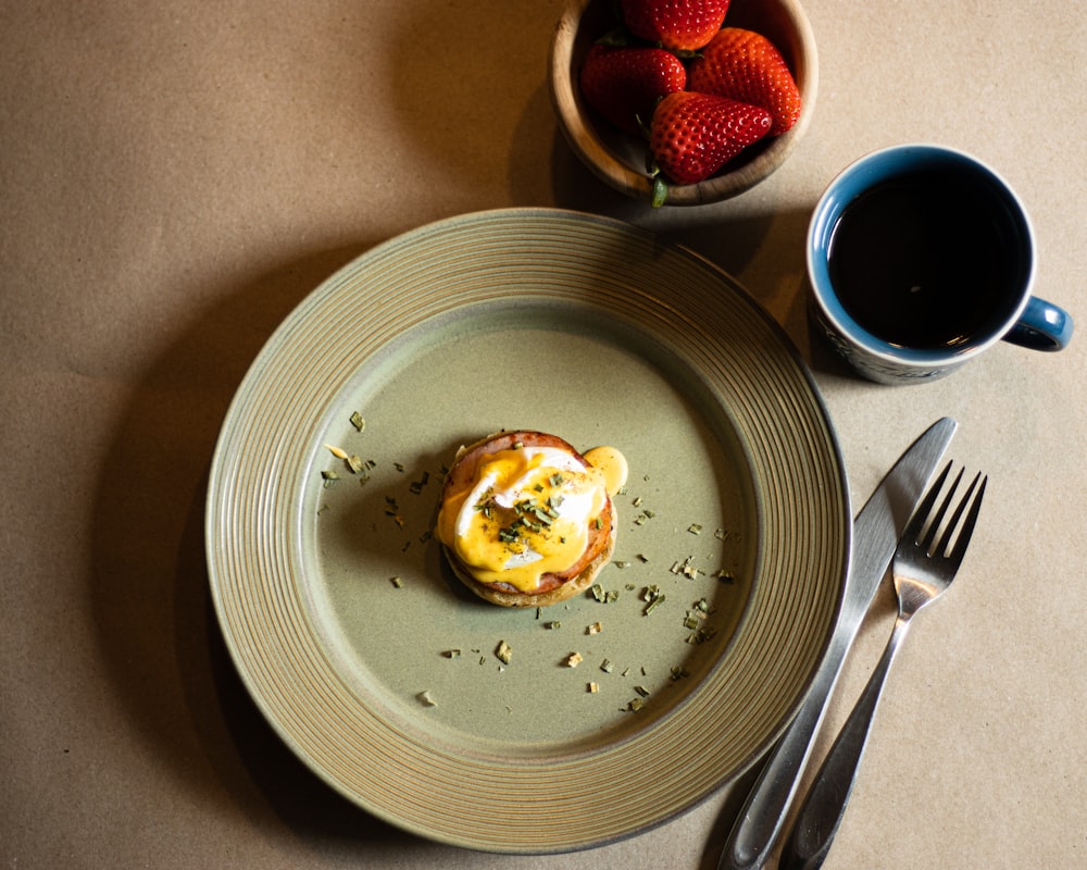 a plate with a pastry on it next to a bowl of strawberries