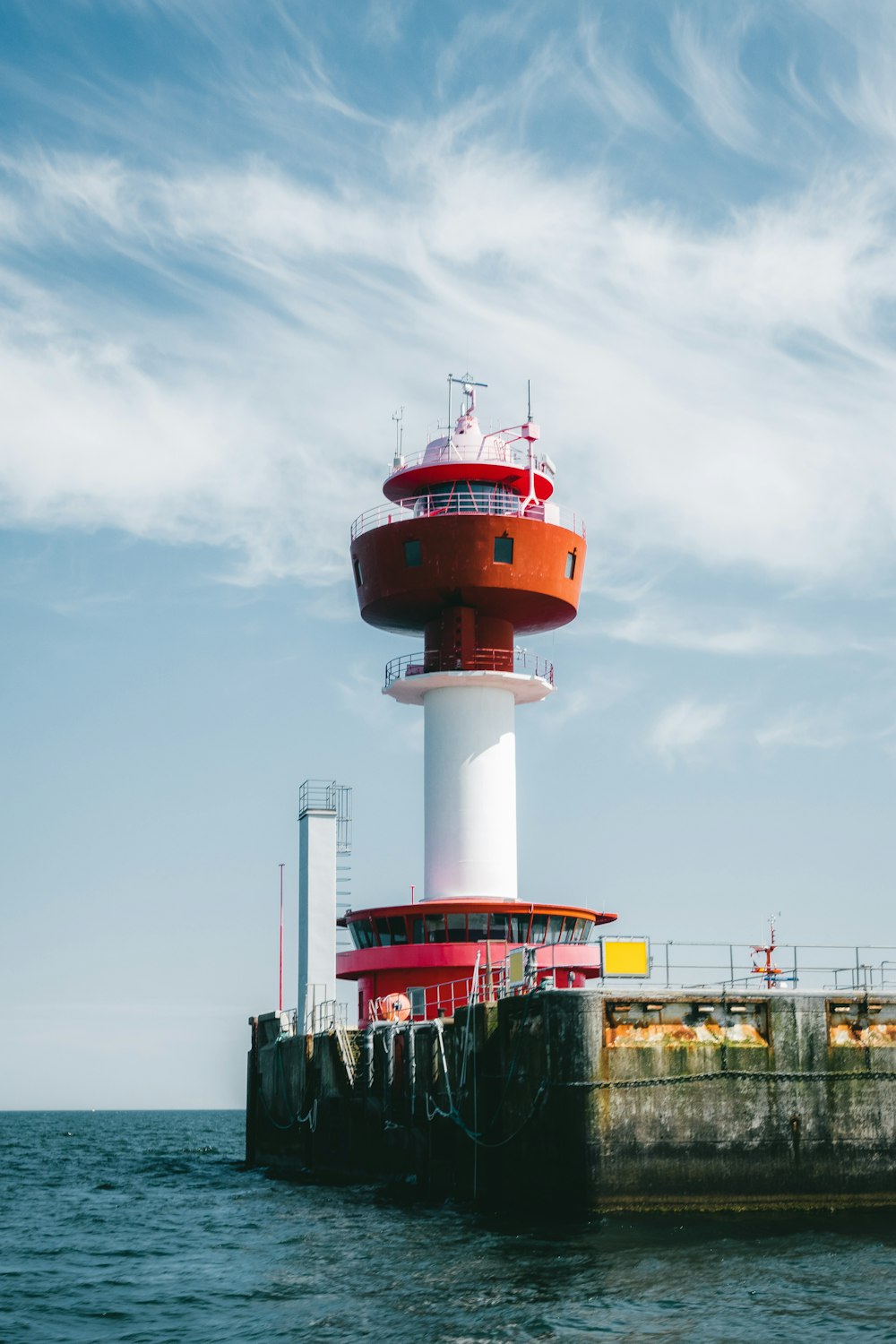 a red and white lighthouse sitting on top of a pier