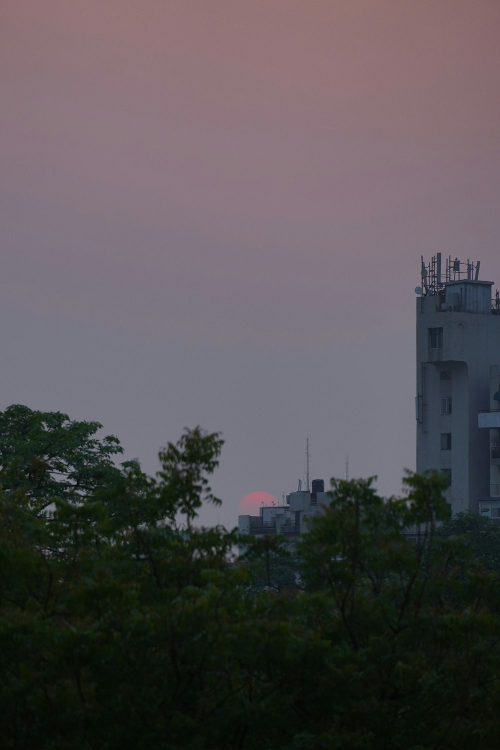 the sun is setting in the distance behind a building