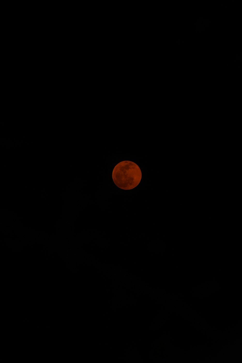 a red moon is seen in the dark sky