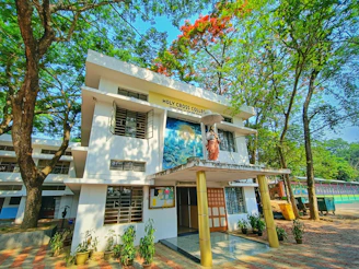 Front view of Charbhuja Chemist College building under clear blue sky, showing entrance and greenery.