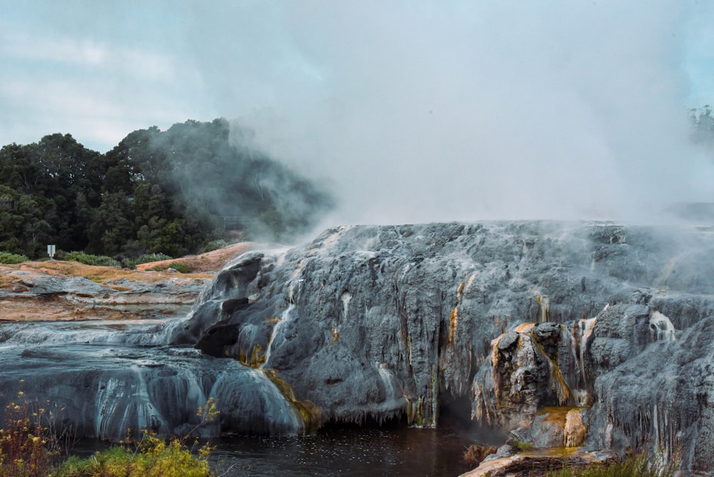 a geyser spewing water into a river surrounded by rocks