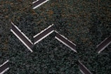Aerial view of a series of solar panels embedded within dense green foliage, arranged in a geometric zigzag pattern.