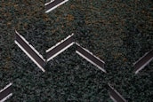 Aerial view of a series of solar panels embedded within dense green foliage, arranged in a geometric zigzag pattern.