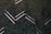 Aerial view of a series of solar panels embedded within dense green foliage, arranged in a geometric zigzag pattern.
