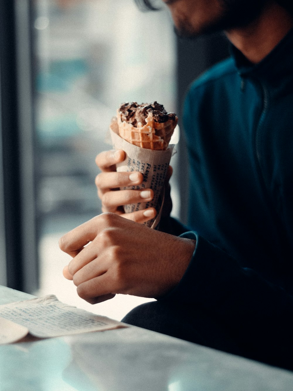 a man sitting at a table eating an ice cream cone