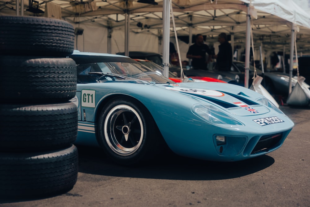 a blue race car parked next to a pile of tires