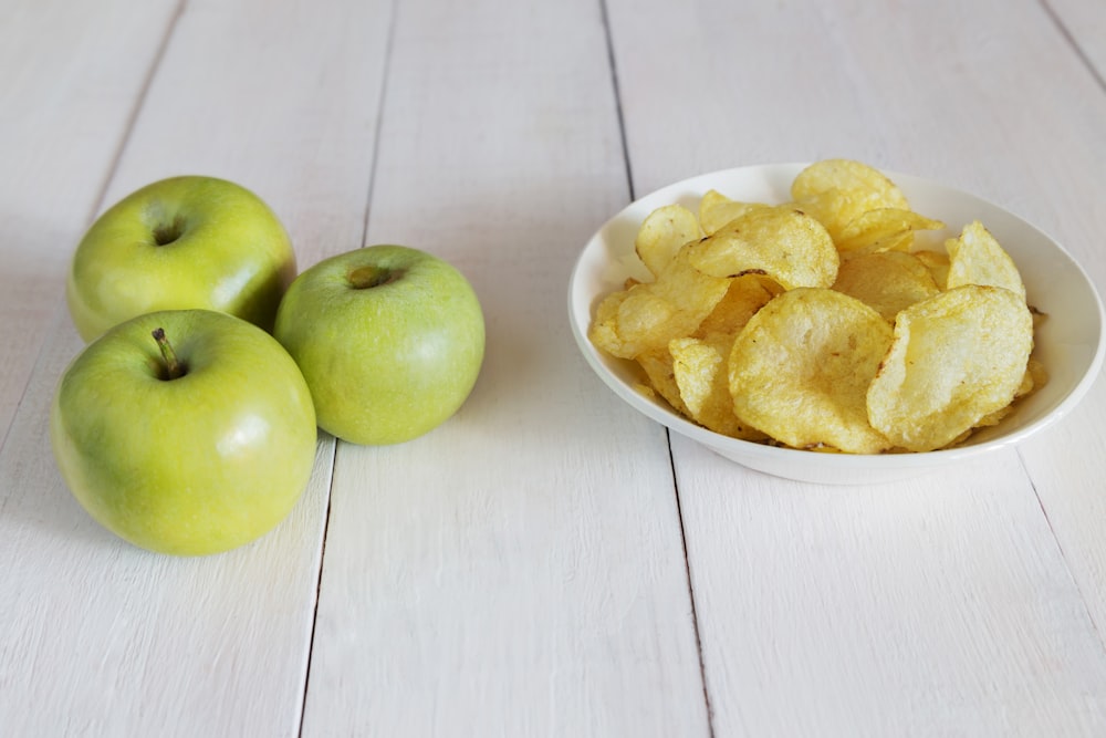 a bowl of chips next to a bowl of apples