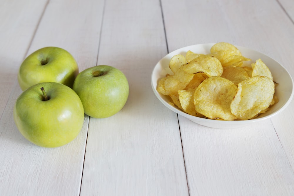 Un tazón de papas fritas junto a un tazón de manzanas