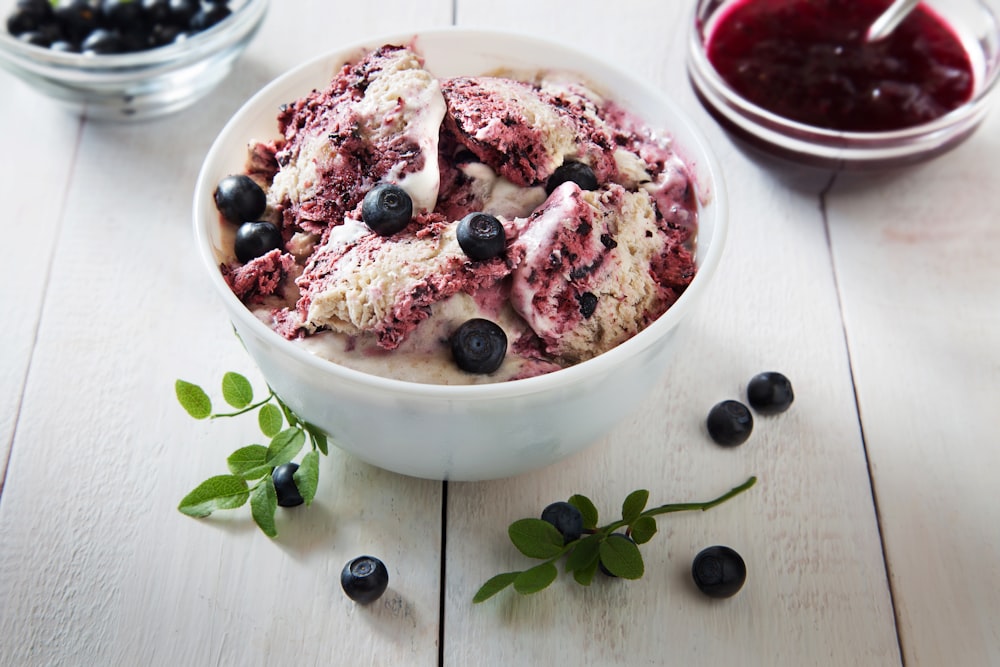 a bowl of ice cream with berries and blueberries