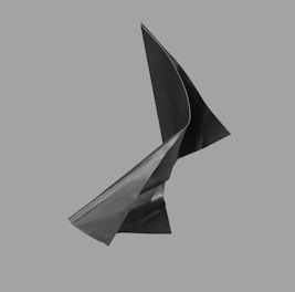 A close-up photo of a helix sculpture with soft shadows on a deep charcoal background, highlighting its delicate curves.