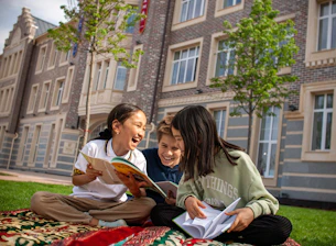 two girls sitting on the grass reading books