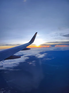 An airplane soaring above clouds with a sunset backdrop, symbolizing new horizons.