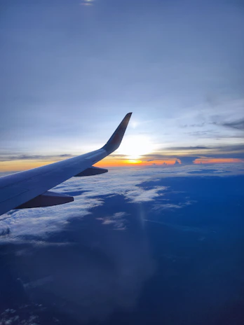 A sleek airplane soaring above clouds with a sunrise backdrop symbolizing new beginnings.