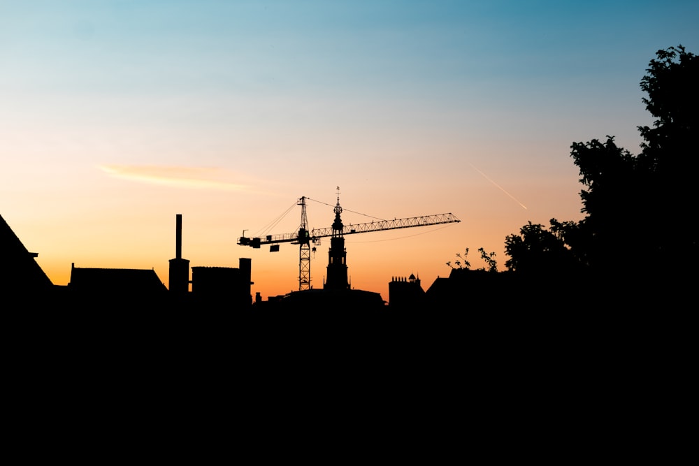 a silhouette of a building with a crane in the background