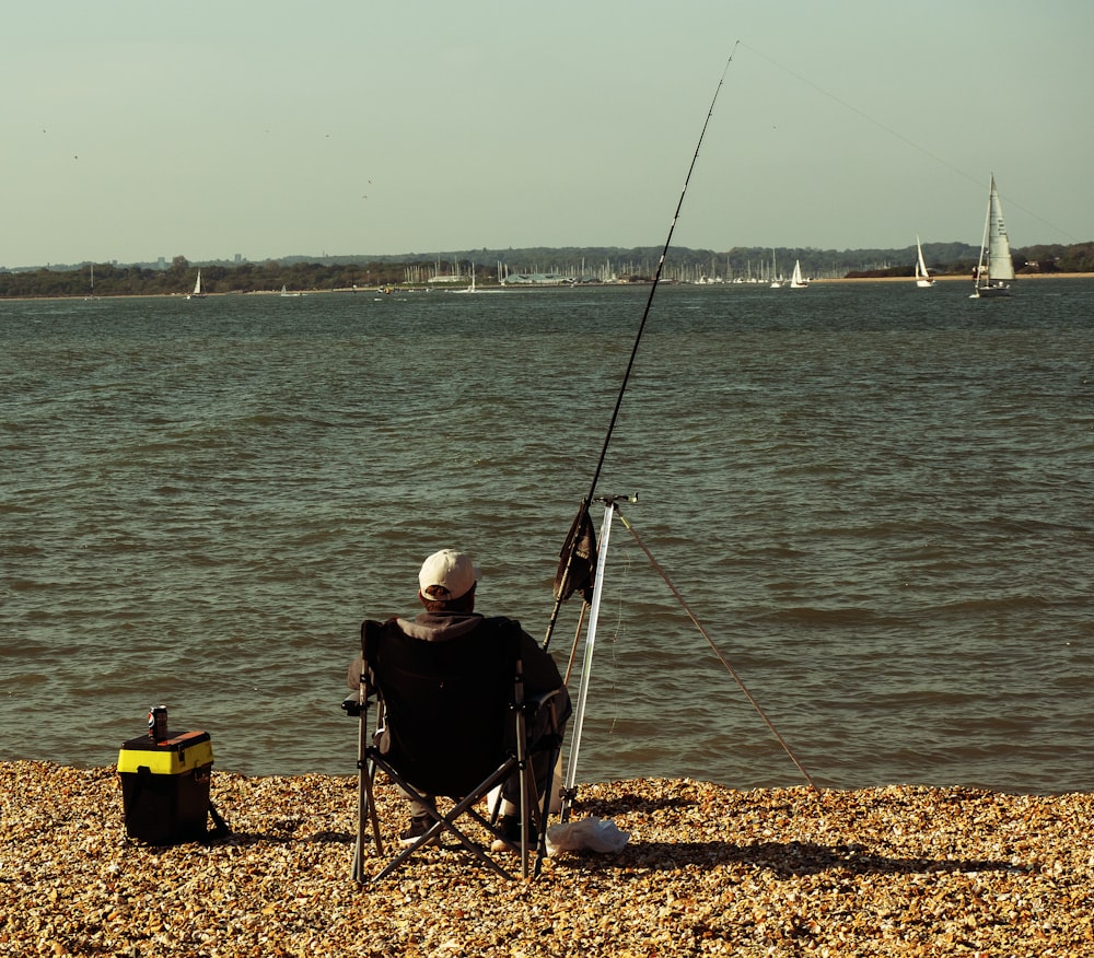 a man sitting in a chair next to a body of water