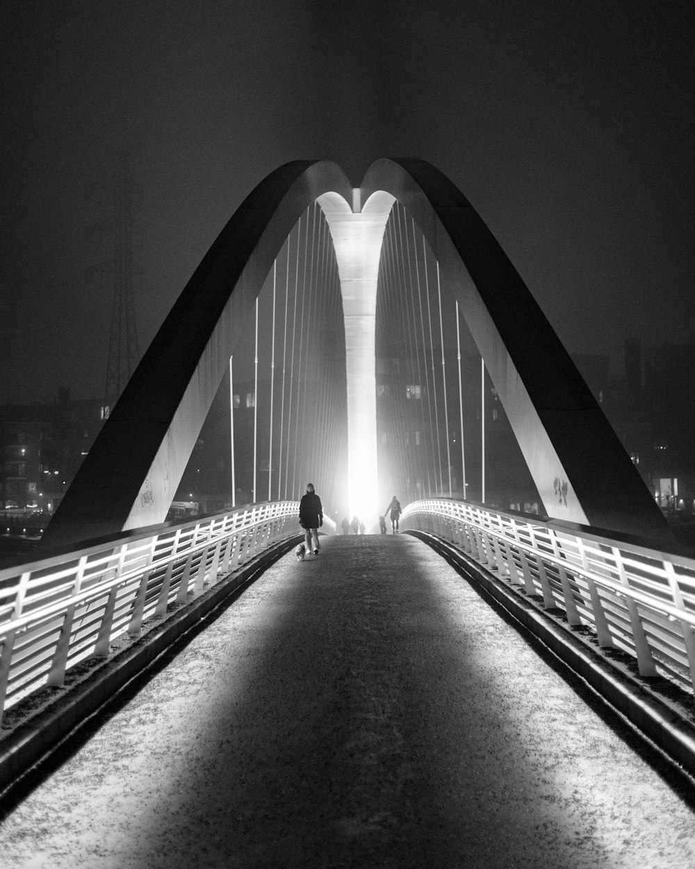 two people walking across a bridge at night
