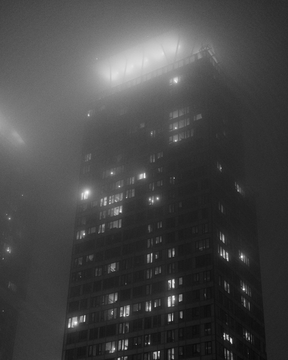 a very tall building with lots of windows in the fog
