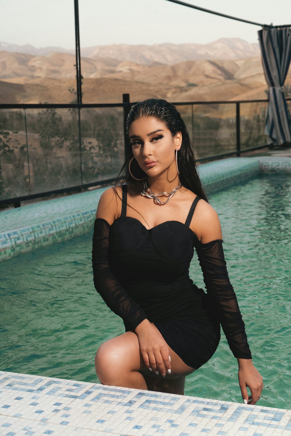 a woman in a black dress sitting in a pool