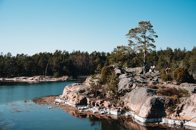A serene coastal scene with a small group hiking along a sunlit trail overlooking the Mediterranean Sea.