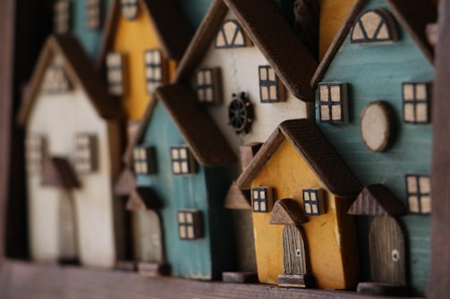 A collection of small, colorful wooden houses is closely arranged. Each house features detailed elements such as roofs, windows, and doors, showcasing a quaint and charming aesthetic.