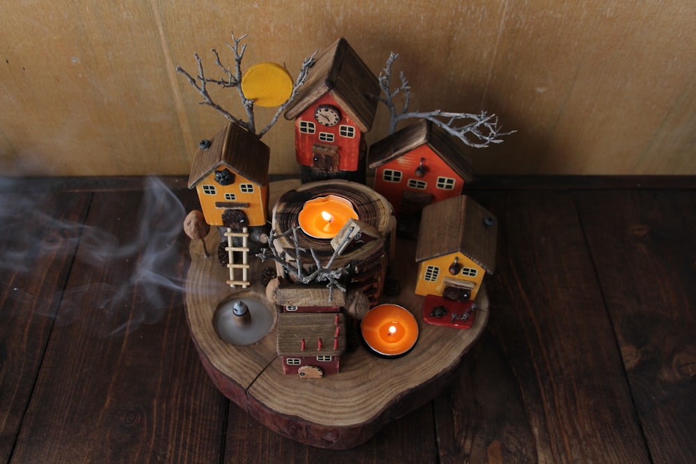 a wooden table topped with candles and houses