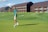 a man walking across a lush green golf course