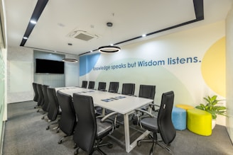 a conference room with a white table and black chairs