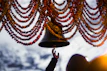 Hands holding a traditional bell above an altar decorated with flowers and holy books.