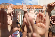 Hands raised in unison as the group dances beneath a clear blue sky.