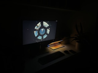 A dark-themed workspace featuring a glowing computer screen.