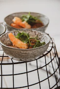 Artistic arrangement of shrimp dip served in a ceramic bowl with fresh herbs on a dark background.