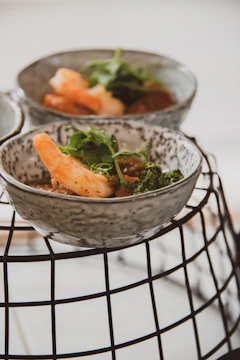 Artistic arrangement of shrimp dip served in a ceramic bowl with fresh herbs on a dark background.