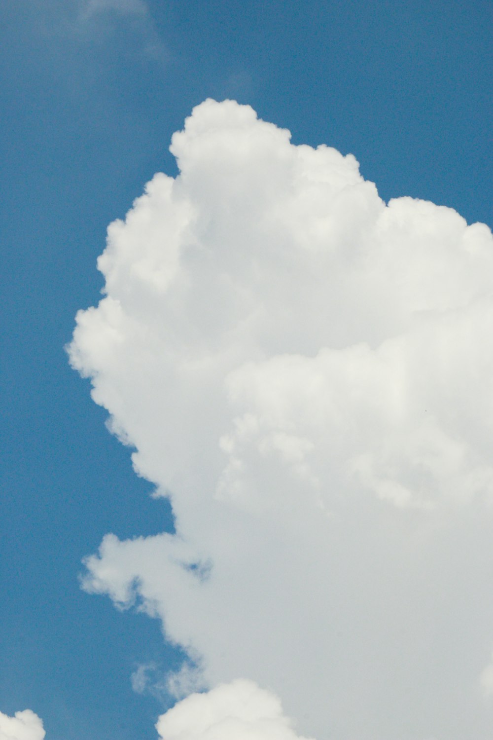 a plane flying through a blue cloudy sky